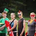 Counselors lined up in superhero costumes outside a cabin, ready to lead a themed all-camp event at Camp Akeela in Vermont